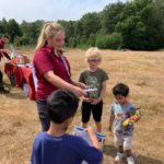 Photo of Warden Zoe handing out the scavenger hunt worksheets to a group of boys.