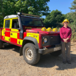 Photo of a warden beside a Fire & Rescue Service Land Rover
