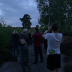 Photo of a group at dusk, cupping their hands behind their ears to better hear the Nightjars churr!
