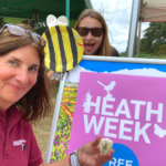 Photo of Warden Nicky and Ranger Mads in front of the Heath Week sign.