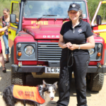 Photo of a lady in front of a Fire Service Land Rover, with collie dog.