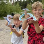 Photo of two young boys proudly showing off the snakes they created in our arts & crafts gazebo!