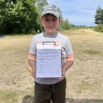 Photo of a boy holding up his answer sheet.