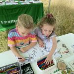 Photo of two small girls working hard on some colouring sheets.