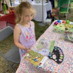 A young child working on a colouring page at an arts and crafts event.