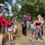 Photo of a crowd of adults and children listening to Education Officer Micheal talking about insects on the heath