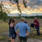 Photo of Warden Steve talking about Nightjars to a small group of adults on an open heath at sunset