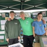 Photo of three countryside workers posing in front of a wildlife display