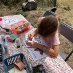 A young girl completing a colouring page of heathland butterfly species at a table for Heath Week 2025 events.