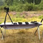 Photo of a table of binoculars and spotting scopes adjacent to an area of open heath